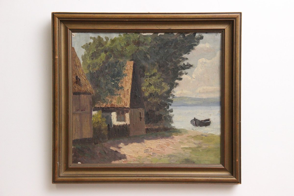 Maleri af hus ved søen i guld ramme.